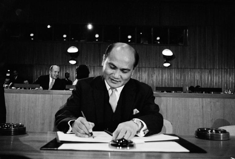A man wearing a suit signs a document.