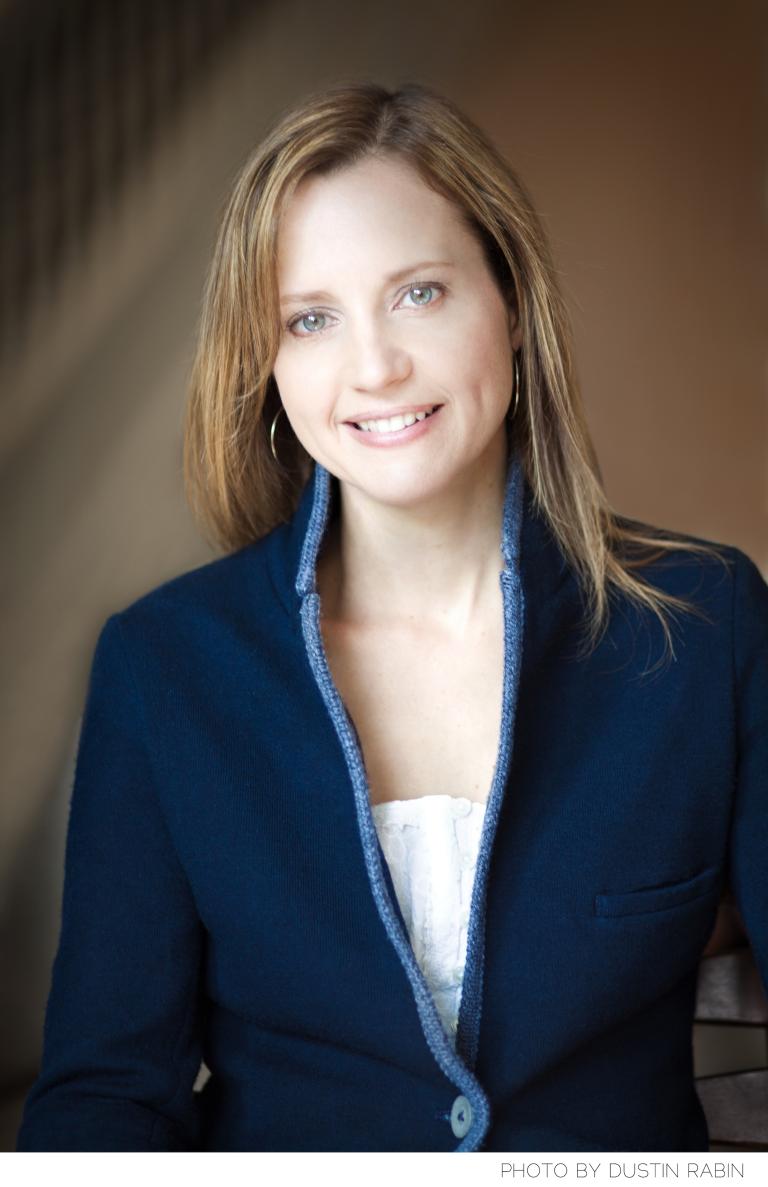Portrait of a smiling woman looking directly at the camera. Partially obscured.