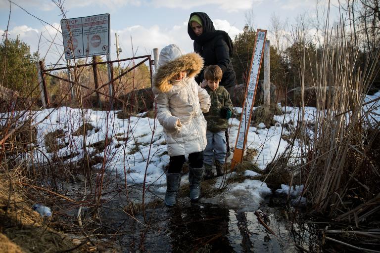 A mother with two children crossing the US-Canada border. Partially obscured.