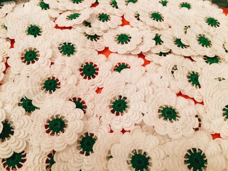 A bunch of knit white flowers with green pistils. Partially obscured.
