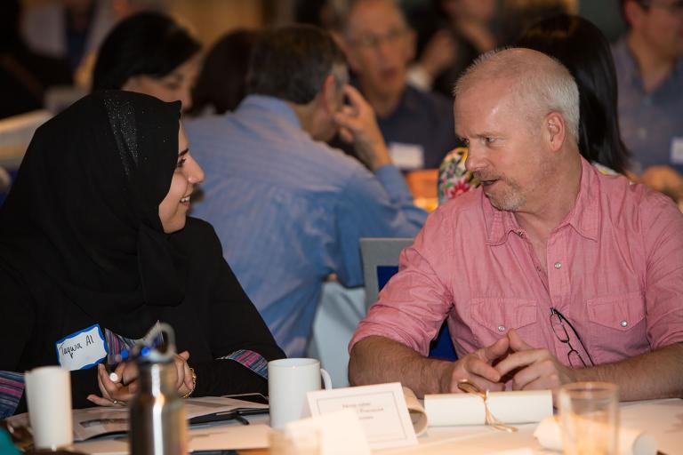 Two people talking at a table. Partially obscured.
