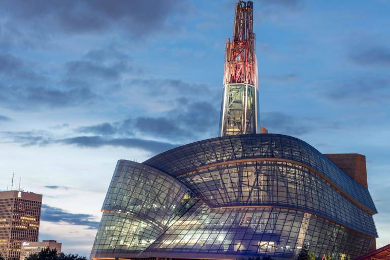An unusual building features a glowing red tower atop a "cloud" of hundreds of glass panes. Partially obscured.