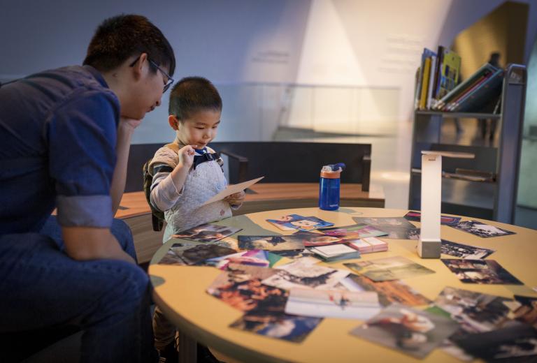 A child and adult looking at a photograph. Partially obscured.