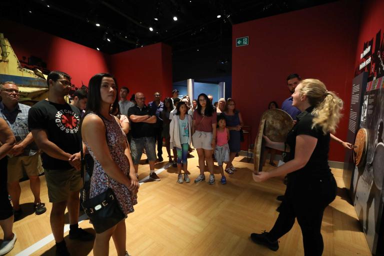 People standing listening to a Museum guide. Partially obscured.