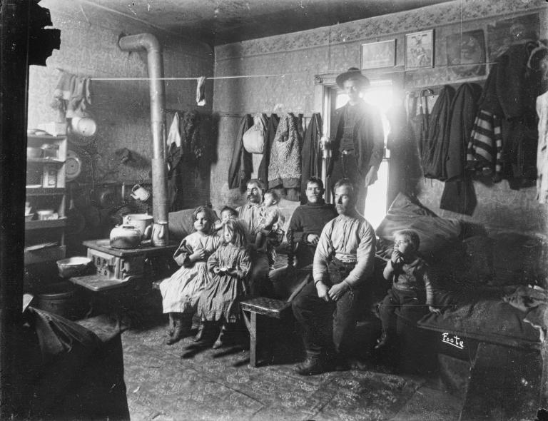 A large family sitting in cramped living space.