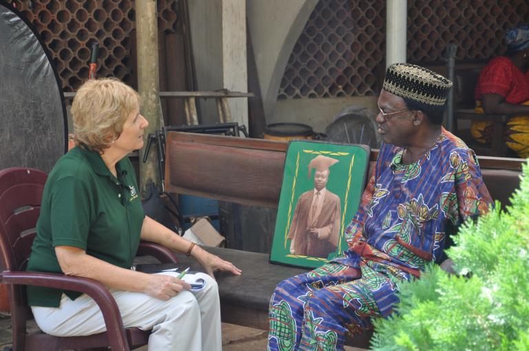 Two people in conversation seated across from each other. Partially obscured.
