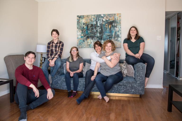 A smiling family of six in a living room. Partially obscured.