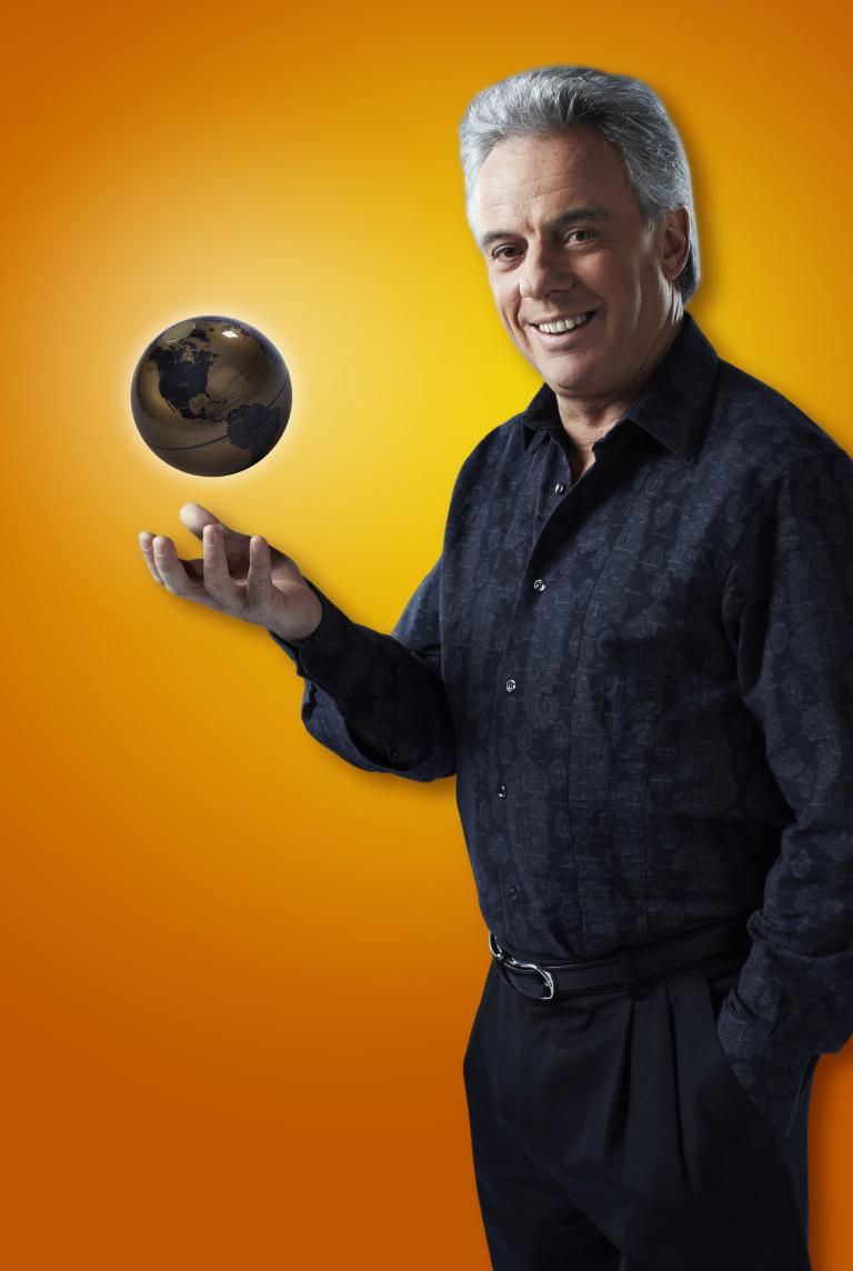 A man looking at the camera tosses up a globe. Partially obscured.