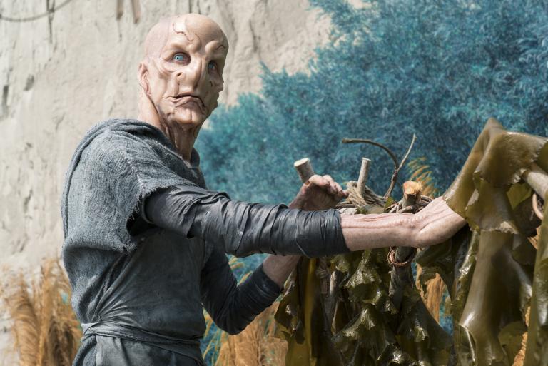 A humanoid alien stands next to a wall. Partially obscured.