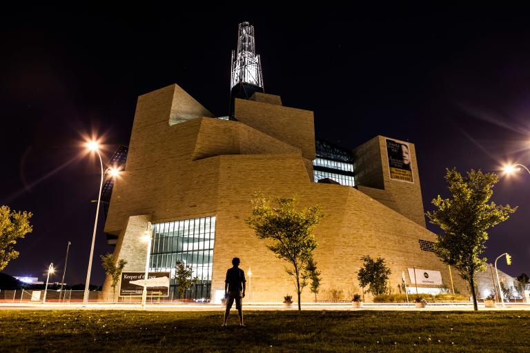  A silhouette of a person faces the exterior north side of the Museum at night (the limestone mountain).