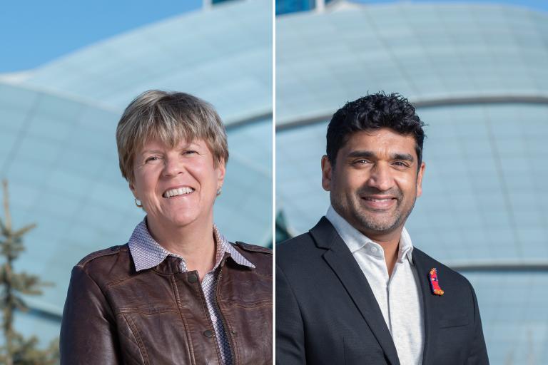 A smiling woman and man stands outside in front of a museum building that features a curved glass facade and a tower. Partially obscured.