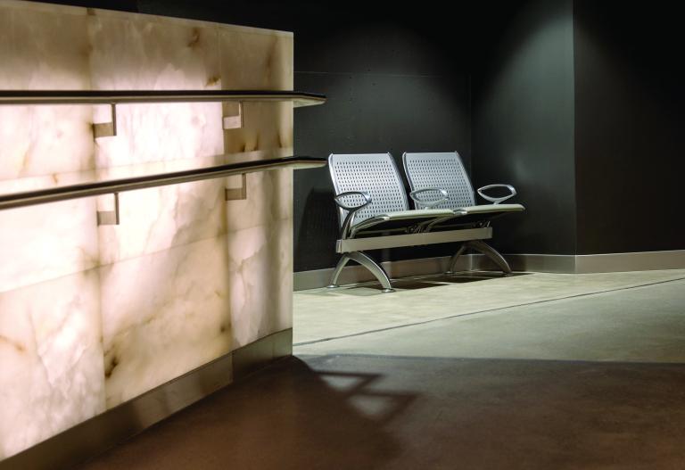 A ramp with railings running parallel to each other at different heights ends next to a two-seat bench.