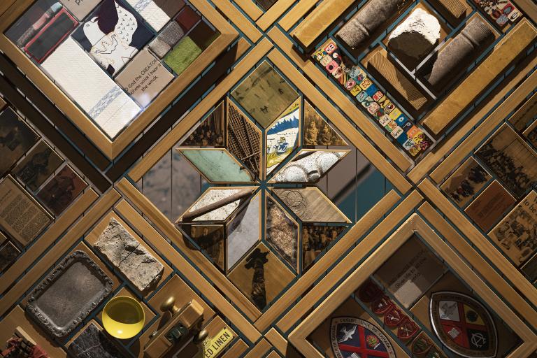 Portion of a large artwork consisting of objects set in cedar frames. Partially obscured.