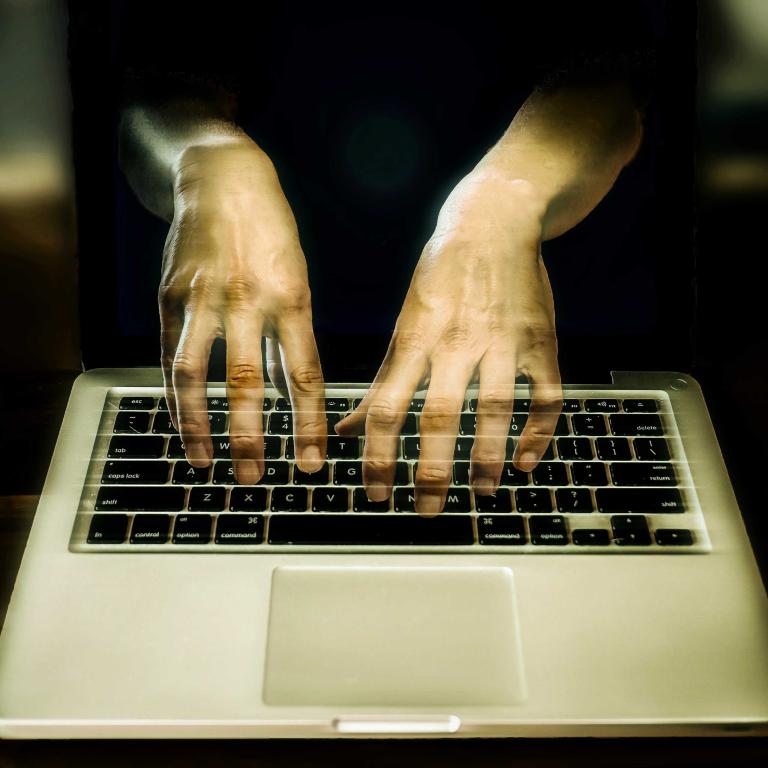 An image of transparent hands hovering over a keyboard. Partially obscured.