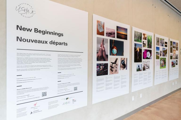 Five panels are hung on a wall. The panels contain written text and images. Partially obscured.