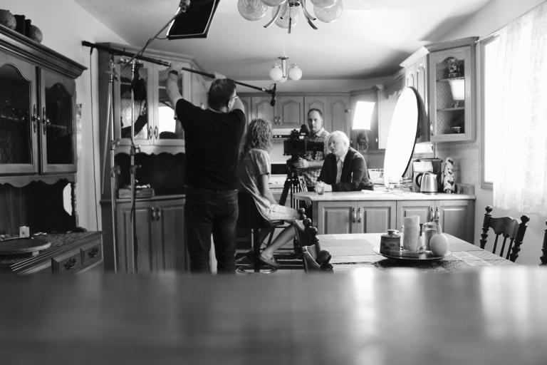 Filming a scene of the movie Fruit Machine, 2 people conversing at a kitchen counter. Partially obscured.