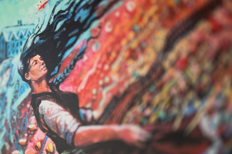 A black-haired woman appears to be in an abstract, colourful windstorm with red and blue. Partially obscured.