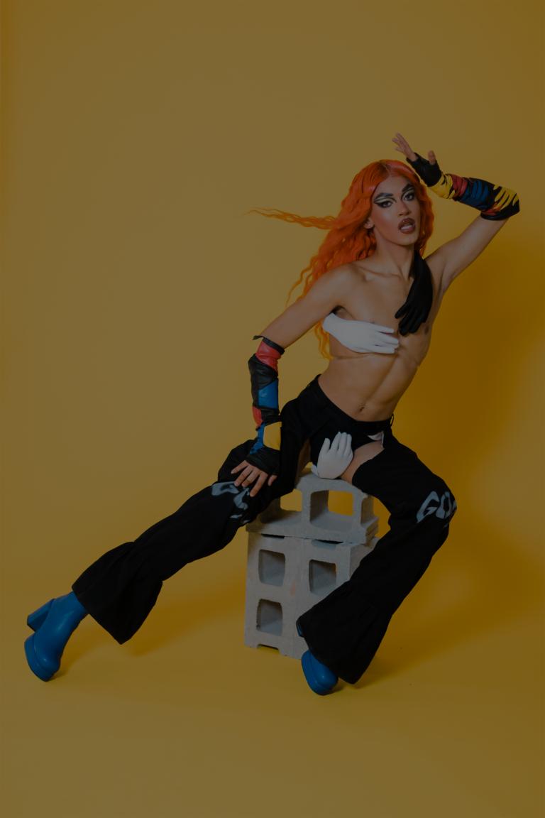 Man with an orange wig, makeup and an eccentric outfit. Partially obscured.