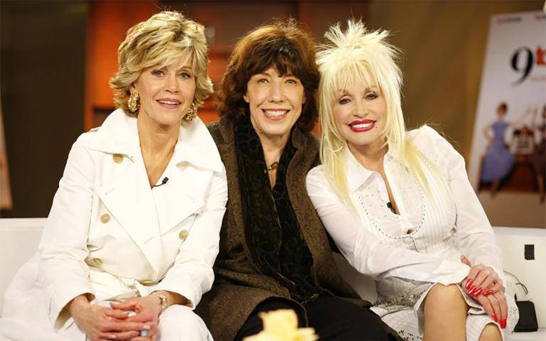 Jane Fonda, Lily Tomlin and Dolly Parton sitting on a couch together. Partially obscured.