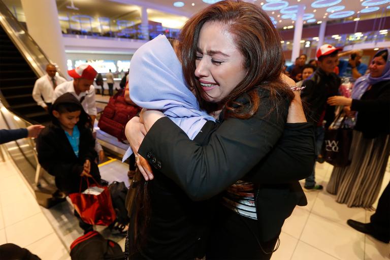 A woman hugs her aunt upon arriving at the Winnipeg airport. Partially obscured.