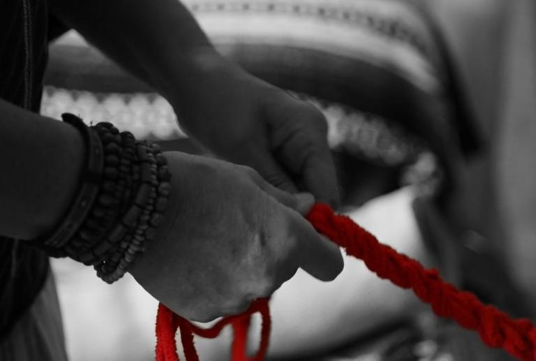 Two hands in black and white hold onto a red rope. Partially obscured.