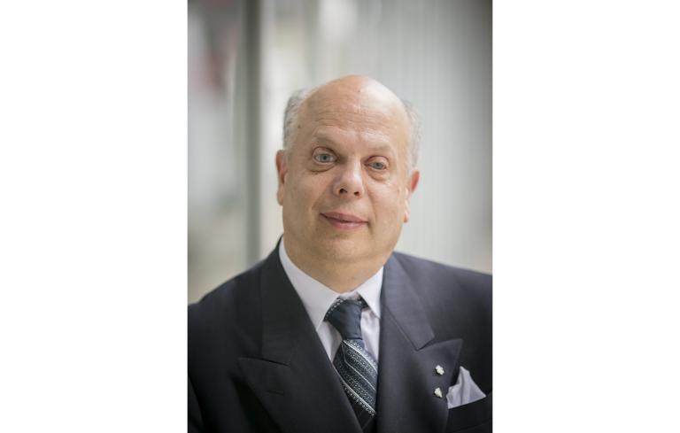 A portrait photo of David Lepofsky, an older man in a suit and tie. Partially obscured.