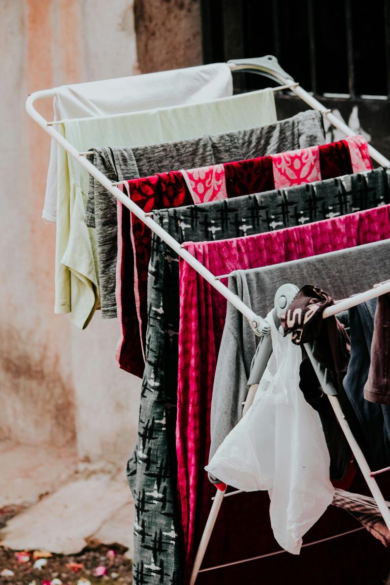 Garments are hung over a rack to air dry. The fabrics are grey, black, white and shocking pink. Partially obscured.