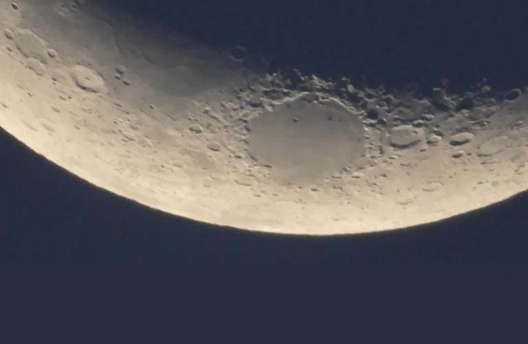 A close-up of a segment of the moon’s surface. Partially obscured.