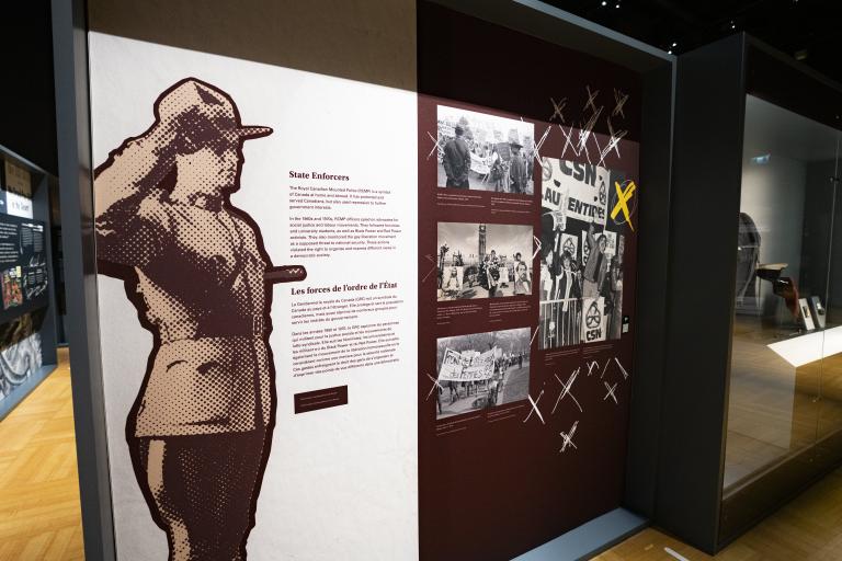 Exhibition panel with an image of an RCMP officer standing at attention and text that read "State Enforcers." Partially obscured.