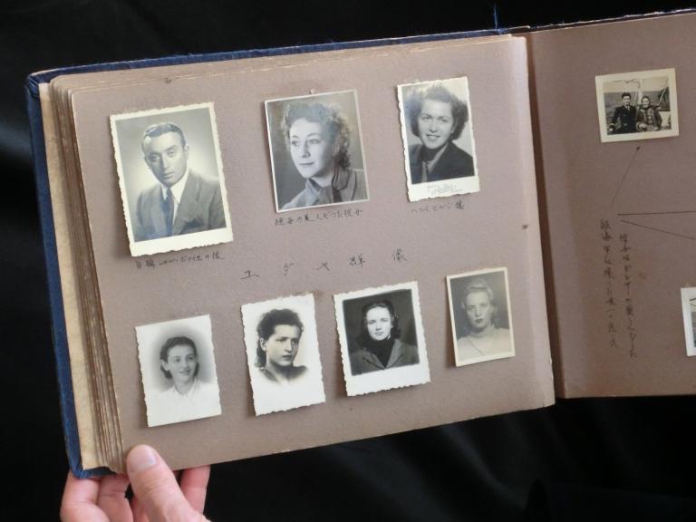 An open photo album contains black-and-white headshots of seven individuals and other annotated photos Partially obscured.