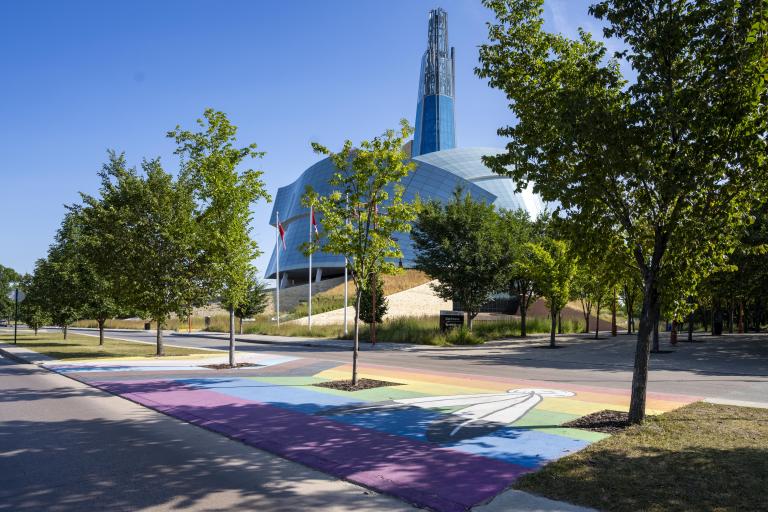 Pride flag pedestrian crosswalk across from the Canadian Museum for Human Rights. Partially obscured.