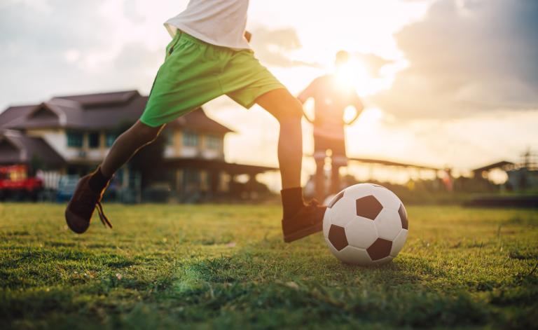Soccer player on field getting ready to kick the ball. Partially obscured.