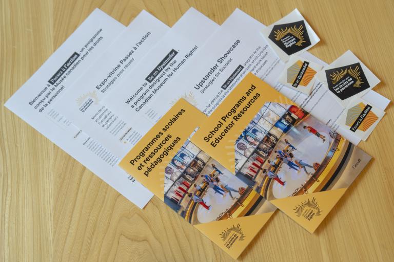 Sheets of paper, booklets and stickers laying on a table. Partially obscured.