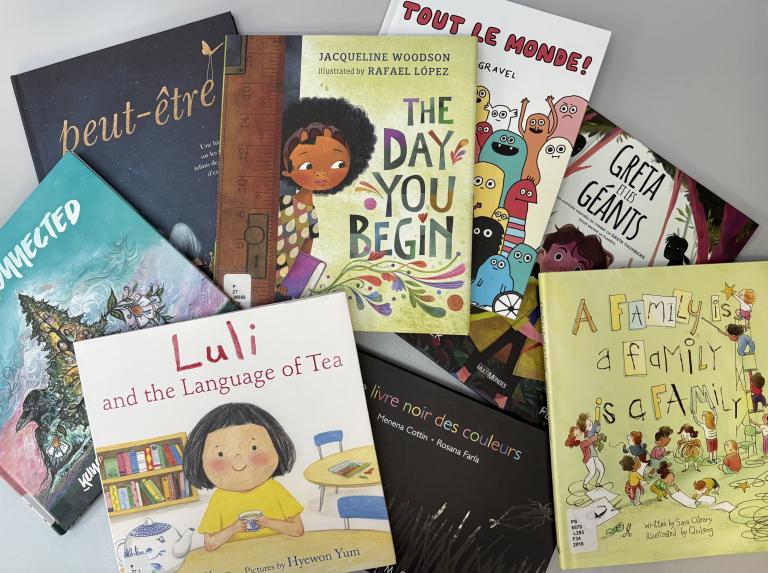 Kids’ books are spread out on a table Partially obscured.