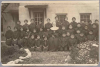A nun and a group of First Nations children in school uniforms posing in front of a stone building.